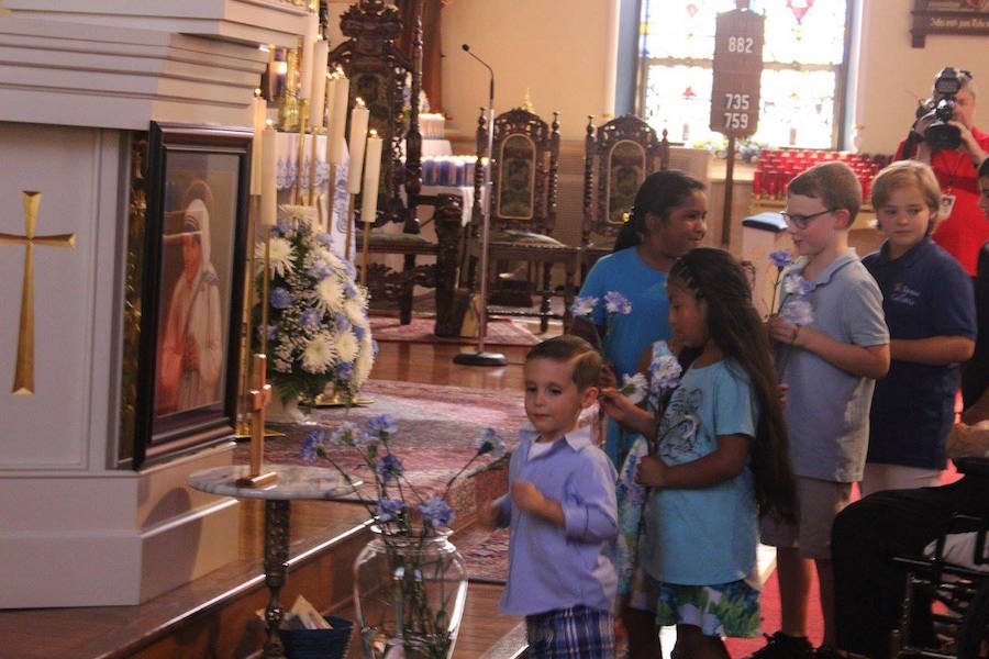 Photo by Debbie Walker of the children of the parish placing flowers before the new picture of Saint Teresa of Calcutta.