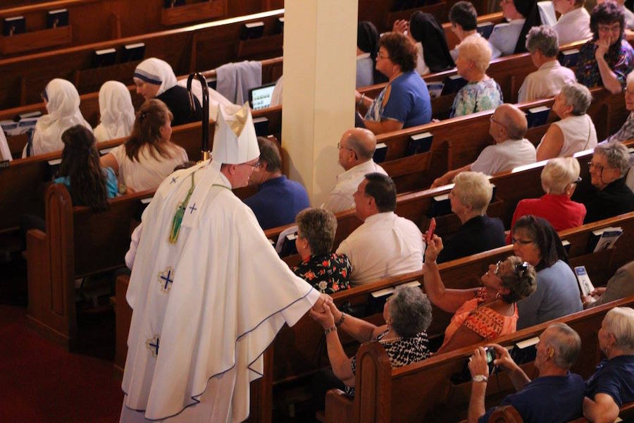 Photo by Debbie Walker of Bishop John Barres talking with people in the congregation before mass.